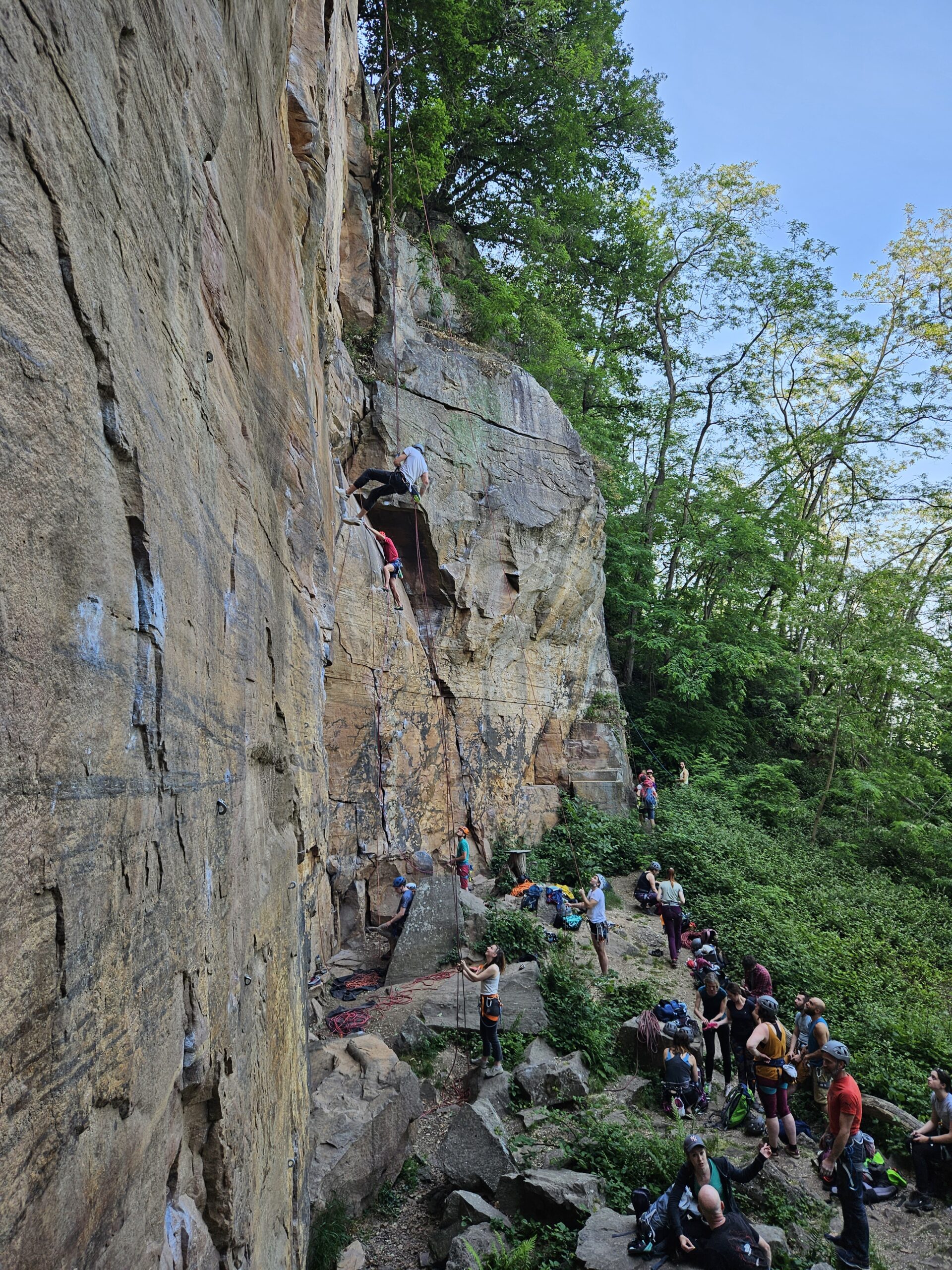 Des grimpeurs au pied et sur les parois de la falaise